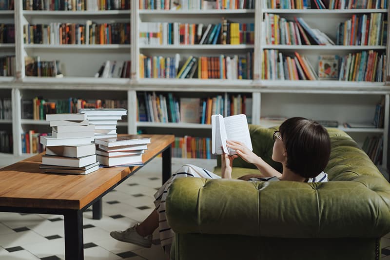 vor Regal auf Sofa lesen